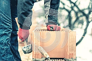 Bricklayer construction engineer fixing bricks and building walls at new house on a cold winter day