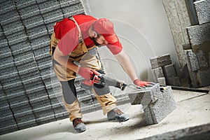 Bricklayer cutting ceramsite concrete blockswith saw at walling