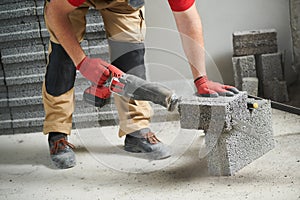 Bricklayer cutting ceramsite concrete blockswith saw at walling