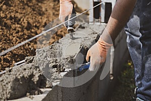 Bricklayer in glove spreading concrete to build a wall on construction site