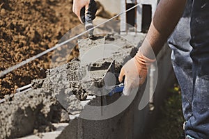 Bricklayer in glove spreading concrete to build a wall on construction site