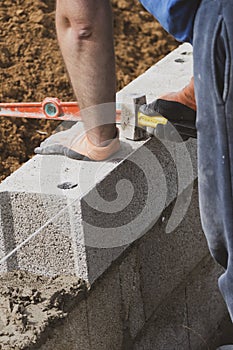 Bricklayer in glove spreading concrete to build a wall on construction site