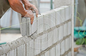 Bricklayer hands installing brick block on construction site