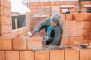 Bricklayer industrial worker installing brick masonry on exterior wall