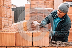 Bricklayer industrial worker installing brick masonry on exterior wall with trowel putty knife