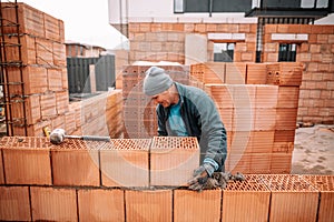 Bricklayer industrial worker installing new bricks. masonry on exterior wall