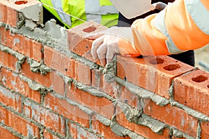 Bricklayer laying bricks on mortar on new residential house construction