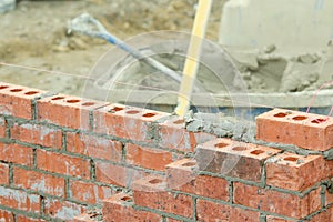 Bricklayer laying bricks on mortar on new residential house construction