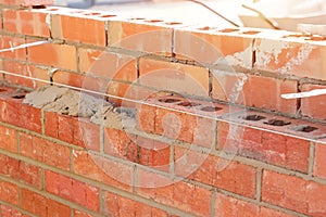 Bricklayer laying bricks on mortar on new residential house construction