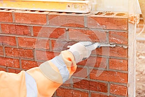 Bricklayer laying bricks on mortar on new residential house construction