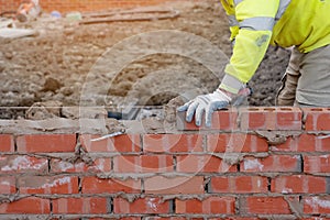 Bricklayer laying bricks on mortar on new residential house constructiona