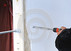 Bricklayer making an undercut for electrical conduits in the wall with an electric hammer