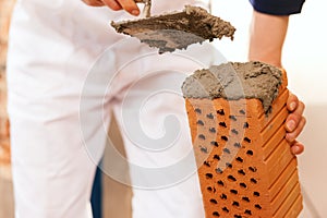 Bricklayer making wall with brick and grout photo