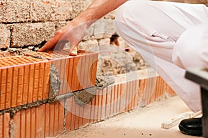 Bricklayer making wall with brick and grout