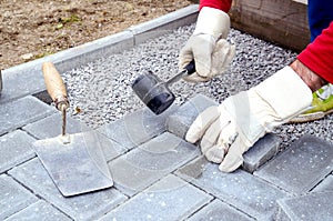 Bricklayer places concrete paving stone blocks for building up a