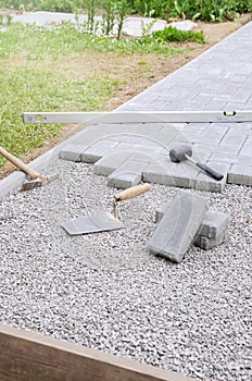 Bricklayer places concrete paving stone blocks for building up a