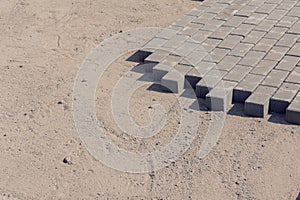 Bricklayer places concrete paving stone blocks for building up a Sidewalk pavement