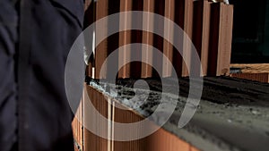 Bricklayer putting down another row of bricks at the construction site. Stock footage. Close up of a man in protective