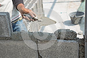 Bricklayer putting down another row of bricks in site