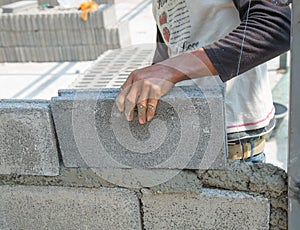 Bricklayer putting down another row of bricks in site