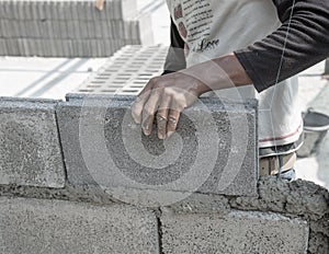 Bricklayer putting down another row of bricks in site