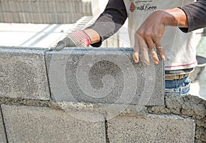 Bricklayer putting down another row of bricks in site
