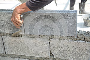 Bricklayer putting down another row of bricks in site
