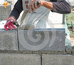 Bricklayer putting down another row of bricks in site