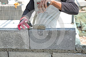 Bricklayer putting down another row of bricks in site
