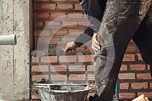 Bricklayer with trowel to installing red bricks masonry and PVC pipe in a new wall