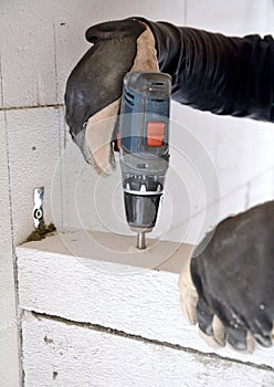 Bricklayer using a battery screwdriver