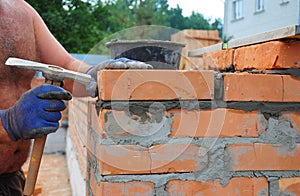 Bricklayer Using a Bricklaying Hammer to Build New Red Brick Wall Outdoor. Bricklaying Basics Masonry Techniques.