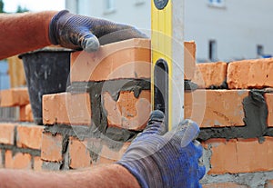 Bricklayer Using a Spirit Level to Check New Red Brick Wall Outdoor. Bricklaying Basics Masonry Techniques