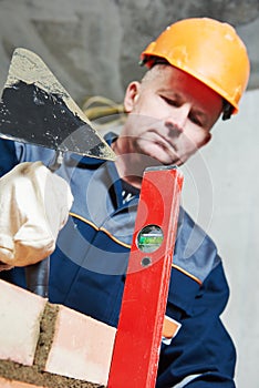 Bricklayer at work with level and trowel