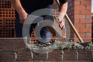 Bricklayer worker installing brick masonry on exterior wall