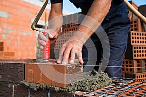 Bricklayer worker installing brick masonry on exterior wall