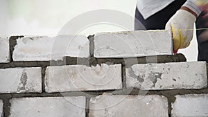 Bricklayer worker installing brick masonry on exterior wall