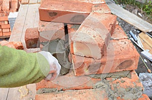 Bricklayer Worker Installing Red Blocks and Caulking Brick Masonry Joints Exterior Wall with Trowel putty Knife. Bricklaying Mason