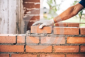 Bricklayer worker placing bricks on cement while building exterior walls, industry details