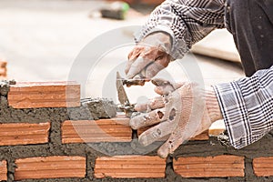 Bricklayer working in construction site of a brick wall
