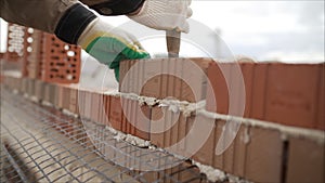 Worker puts a brick wall. Bricklayer working in construction site of a brick wall. Bricklayer putting down another row of bricks