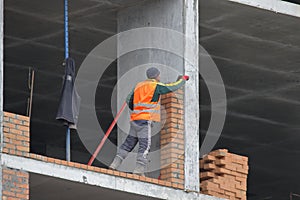 A bricklayer works at a construction site. Work is underway to lay a red brick wall. A new house is being built.