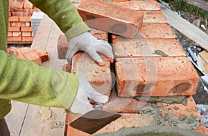 Bricklayers hands in masonry gloves bricklaying on House Construction Site. Bricklaying, Brickwork.