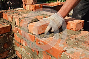 Bricklayers hands in masonry gloves bricklaying house wall. Bricklaying,  Masonry, Brickwork close up