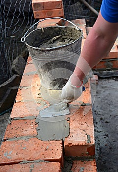 Bricklayers hands in masonry gloves bricklaying new house wall. Bricklaying house wall