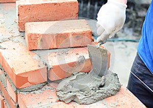 Bricklayers hands in masonry gloves bricklaying new house wall. Bricklaying house wall