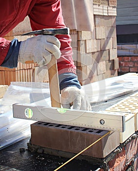 Bricklayers hands with in masonry trowel bricklaying new house wall on foundation. Close up of industrial bricklayer installing