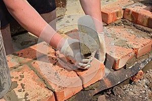 Bricklayers hands with in masonry trowel bricklaying  new house wall on foundation photo