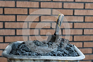 Bricklayers trowel in fresh mortar with bricks wall n the background