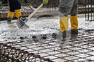 Bricklayers who level the freshly poured concrete to lay the foundations of a building photo